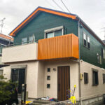 オレンジがアクセントカラーとなった緑と淡いオレンジに塗り分けられた戸建て住宅