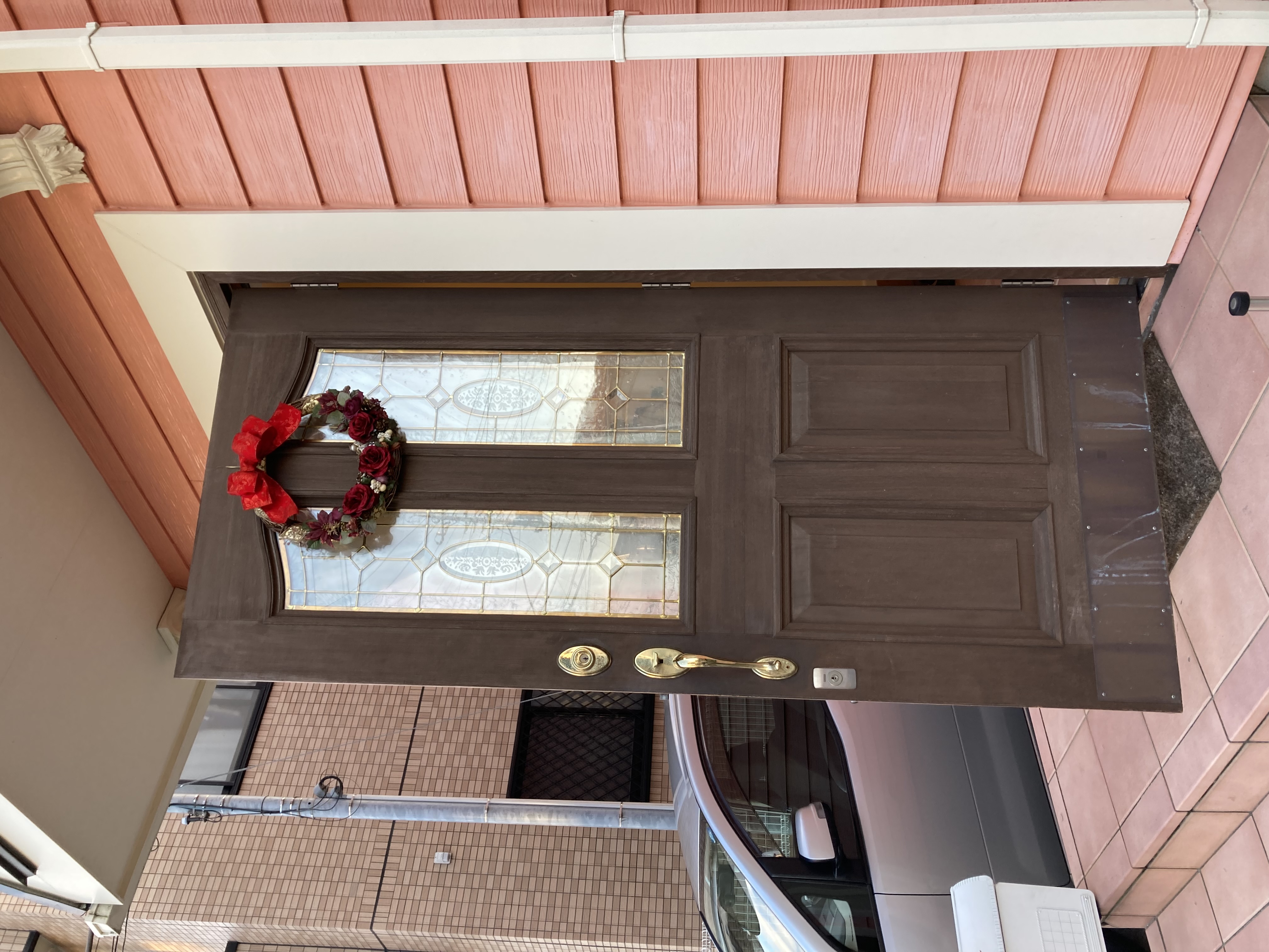 越谷市蒲生南町ピンクの外壁のお住いのクリスマスリースのかかった玄関ドア