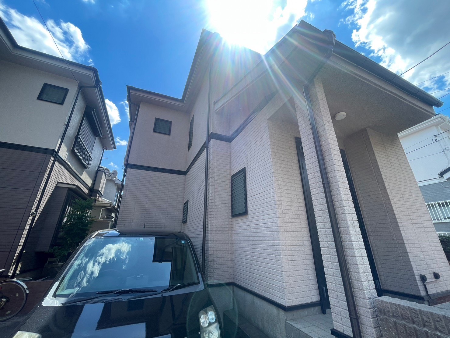 淡いピンクい色の外壁をした2階建ての戸建て住宅