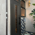 ガラス窓付きのドアとタイルの床が調和した玄関です