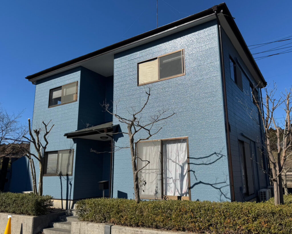 稲敷市江戸崎の青い家とその前にある木。外壁塗装後の新しい印象を伝えています