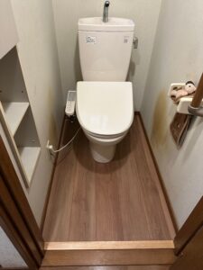 白いトイレの写真　フローリング張り替え後　茶色い木目柄のフローリング
