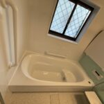 施工後の浴室の写真　右側一面だけ淡い緑色の壁　出入口に手すりがついている