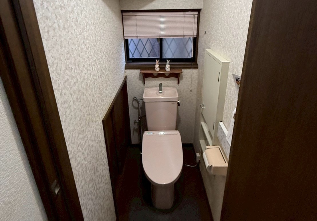 トイレ交換工事施工前の写真ピンクのトイレ背面に小さな窓がある