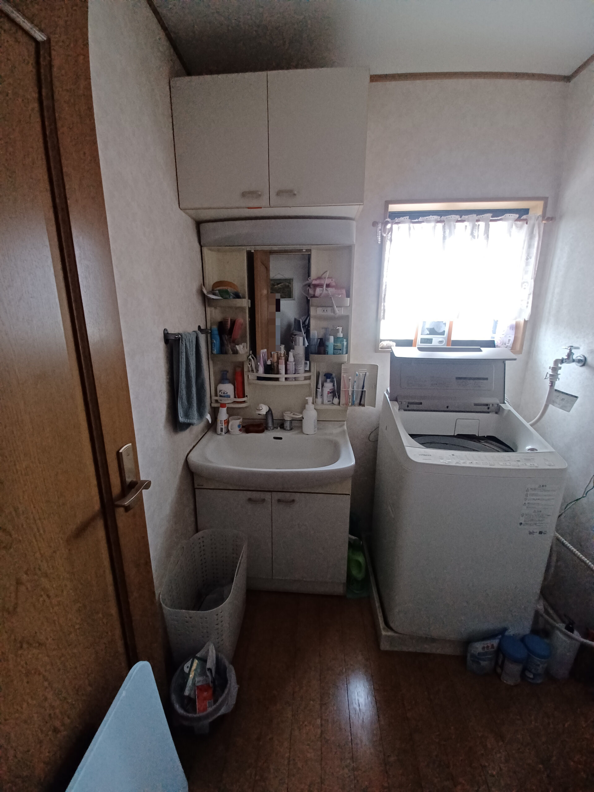 洗面化粧台交換工事の施工前の写真、洗面化粧台は左壁付けに設置されている、真ん中に鏡、両端に収納がついている。